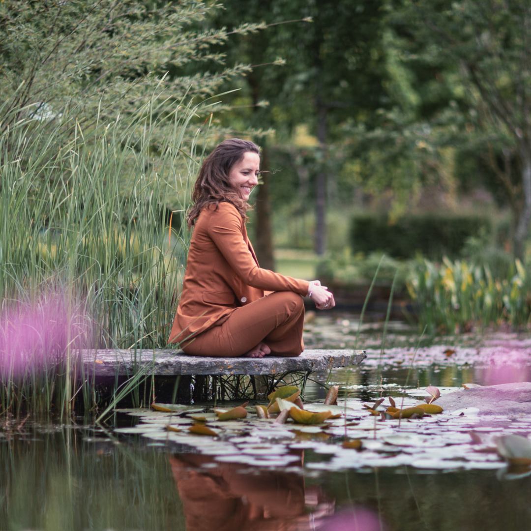 Alicia Zuiderwijk zit bij een vijver in kleermakerszit.